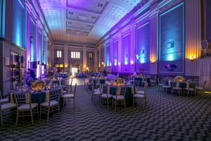 Key Hall at Proctors - wide view of empty room with tables, linens and settings; uplishting illuminating room in purple, yellow and blue colors